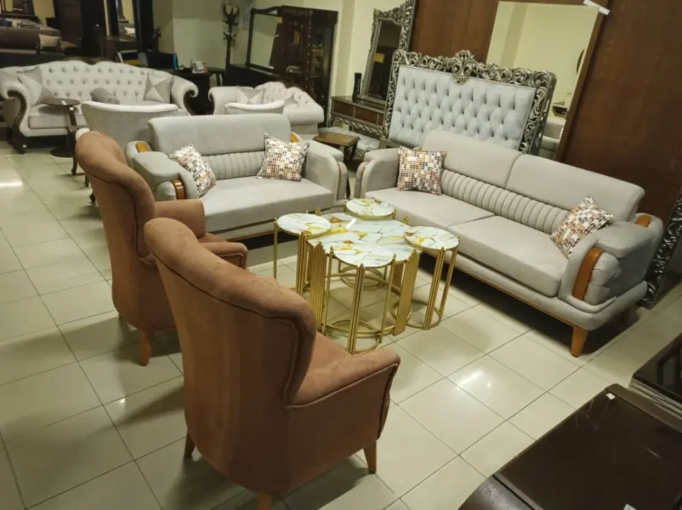 Light grey sofa set with brown wingback chairs and gold nesting tables