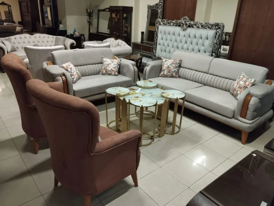Showroom setting of grey sofas, brown chairs and marble-topped gold tables