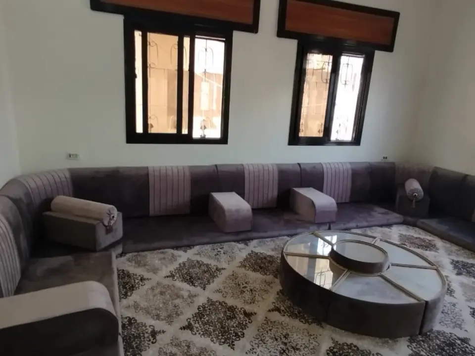 مجلس أرضي رمادي بلمسات مخططة تحت نوافذ بكرانيش خشبية